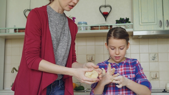 Happy Mother and Cute Daughter Cooking Together and Having Fun Stirring Dough in Hands in Kitchen