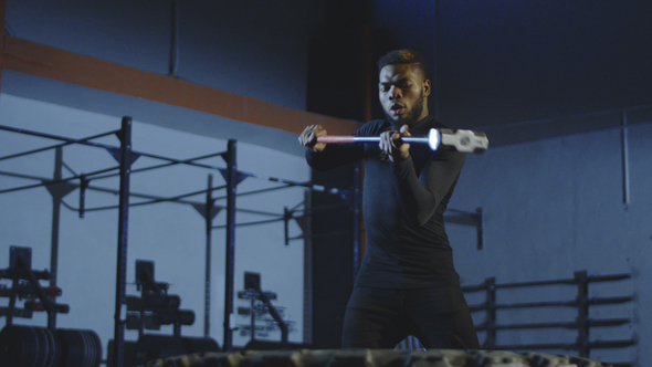 Serious Athletic Man Hitting Tyre with Hammer