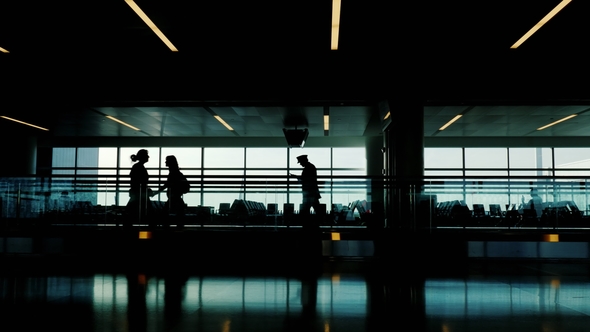 Silhouettes of Passengers in the Airport Terminal. They Drive on a Moving Belt