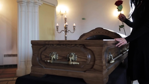 Sad Woman Putting Red Rose into Coffin at Funeral 11