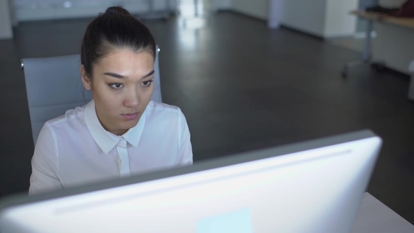 Young Female Employee Is in Working Process, Sitting at Table with Computer,  Looking at Scree