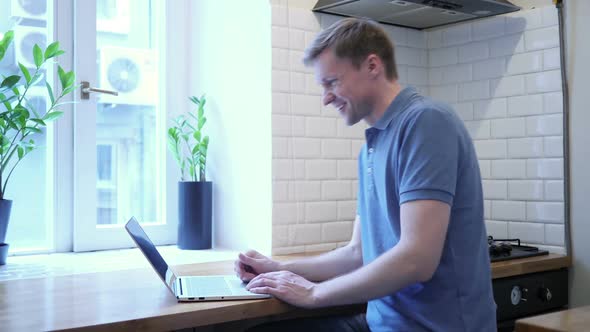 Video Chat on Laptop By Man While Sitting in Kitchen