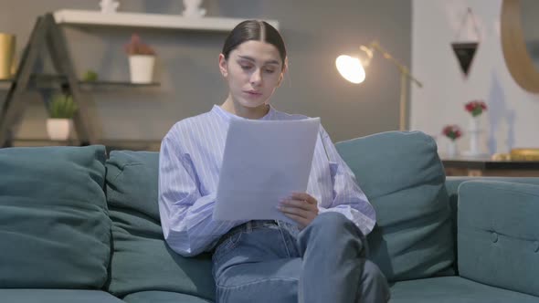 Hispanic Woman Reading Documents on Sofa