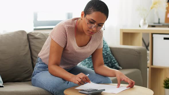 African Woman with Papers and Calculator at Home