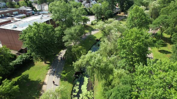 An aerial drone view over a park in Valley Stream, NY with a stream that has algae on it. It is a su