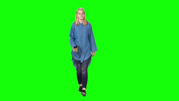 Blonde Teenager Girl Calmly Walking and Drinking Coffee on Green Screen. Chroma Key. Front View