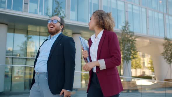 Positive Office Employees Walking Together Outdoors Discussing Project or Chatting