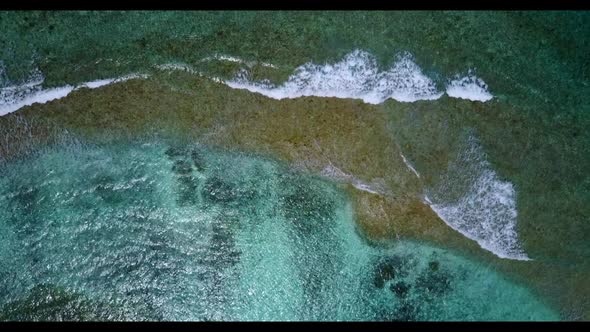 Aerial flying over texture of exotic shore beach break by shallow lagoon with white sandy background