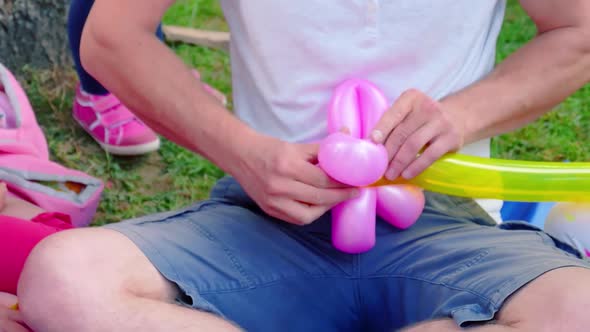 Young, cute Caucasian European man inflates balloon on park background. Concept of fun, picnic, carn