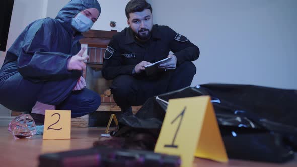 Portrait of Serious Caucasian Police Professionals Discussing Evidence at the Crime Scene