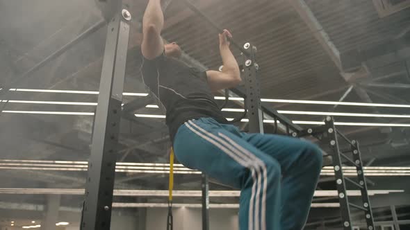 Young Caucasian Athlete Doing a Flip Lift in a Gym with Haze and Modern Lighting