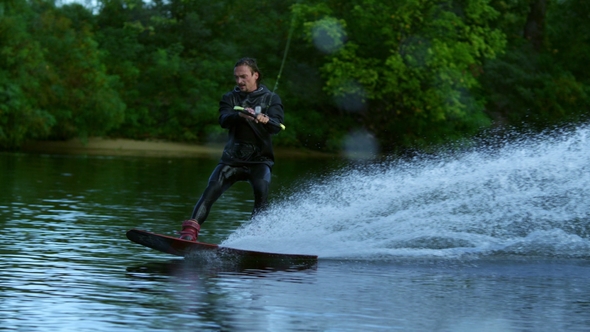 Man Riding Wakeboard on Motorboat Wave. Rider in Training Wake Boarding