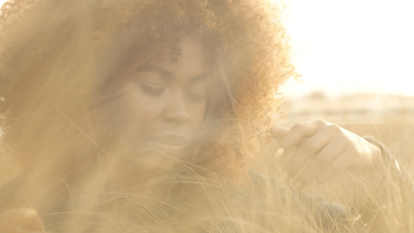 Black Mixed Race Woman with Big Afro Curly Hair in Lawn Field with High Dry Autumn Hay Grass and