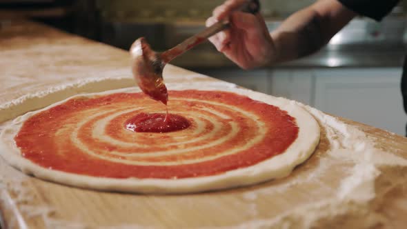 Close Up of Male Hands Spreading Sauce on Pizza Dough