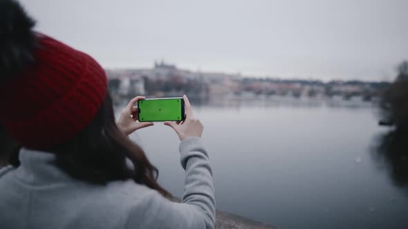 Back Portrait of Young Brunette Woman Holding Smartphone or Mobile Phone with Chroma Key in Hands or