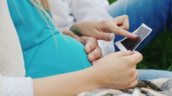 A Pregnant Woman with Her Husband Looking at Ultrasound Picture of Their Future Baby