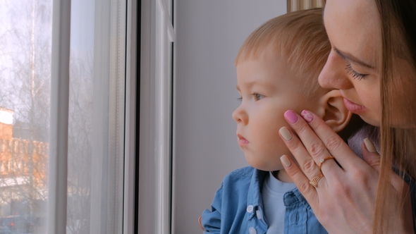 Young Mother and Pensive Little Boy Looking Through Window