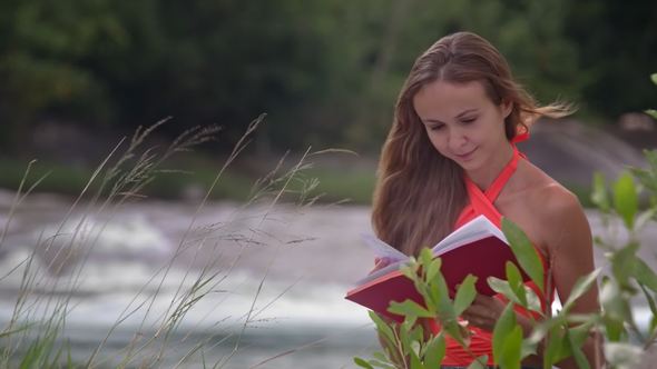 Wind Shakes Girl Hair Reading Book on River Bank