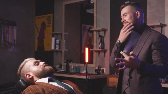 Portrait of Confident Caucasian Barber Male and His Client in Salon