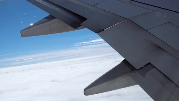 Detail of an Airplane Wing Flying Over Clouds