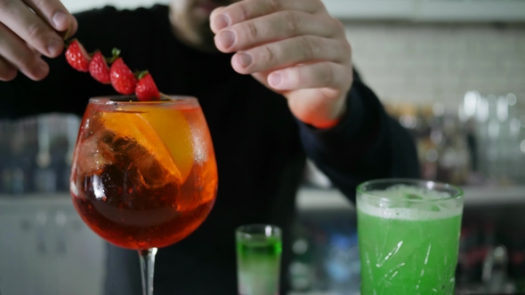 Guy Barkeeper Inserts Black Straws in Glass with Alcoholic Drink with Ice and Fresh Berries
