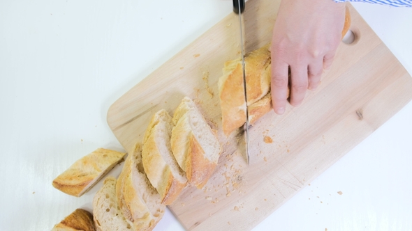Woman Hands Cutting Bread In Kitchen