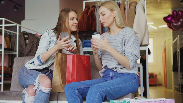 Attractive Girls Are Sitting Together in Women's Clothing Shop. They Are Drinking Coffee, Chatting