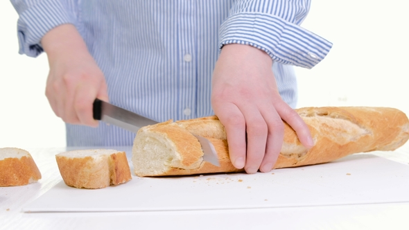 Woman Hands Cutting Bread In Kitchen.  Of Female Hands Holding Knife, Slicing White Baguette O