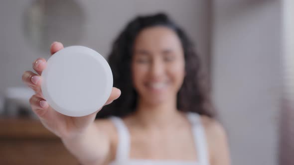 Out Focus Happy Smiling Young Woman Standing in Bathroom Holding Cosmetic Product in Hand