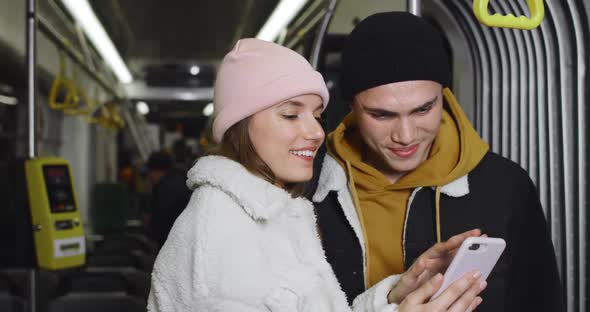 Crop View of Cheerful Couple Talking and Smiling While Looking at Smartphone Screen. Millennilal