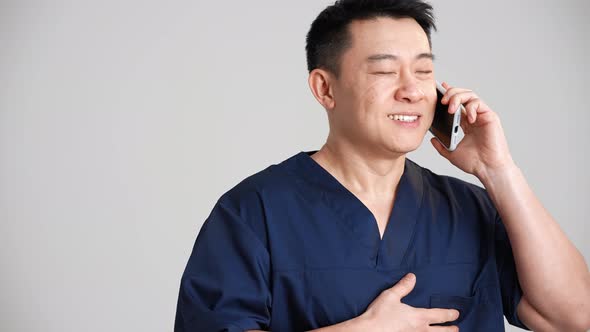 Happy Asian doctor talking with patient by phone