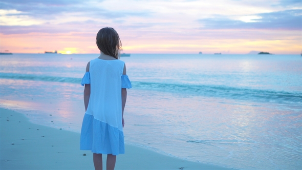 Adorable Happy Little Girl on White Beach at Sunset.