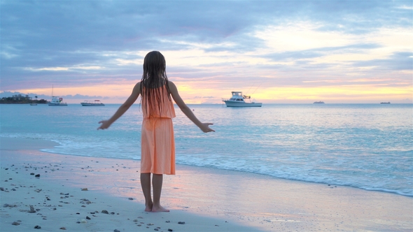 Adorable Happy Little Girl on White Beach at Sunset.