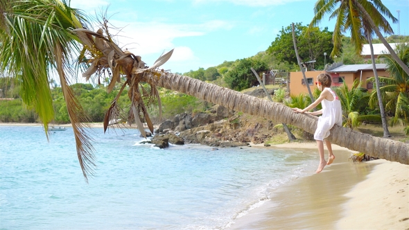 Adorable Little Girl Sitting on Palm Tree During Summer Vacation on White Beach