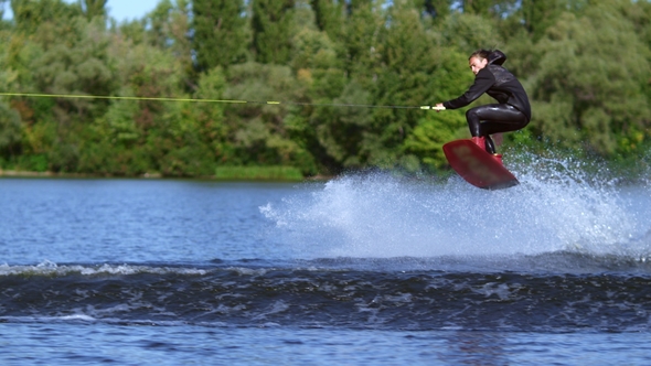 Wakeboarder Jumping Over Water Wave. Slim Man Wakeboarding Above Water