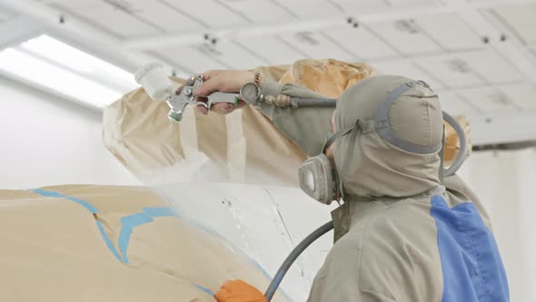 Close View of Spray Gun in Spray Booth in Hands of Painter