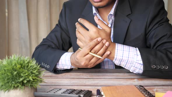 Young Man in Suffering Wrist Pain While Sited on Office Desk