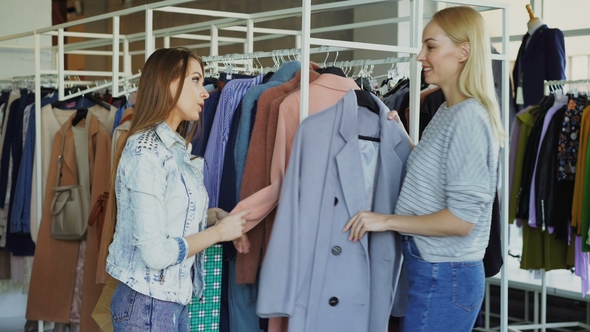 Shop Assistant Is Helping Young Woman, Bringing Her Coat and Telling About Model