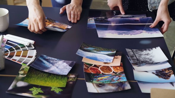 Tilt-up Shot of Women's Hands Placing Photos on Table in Modern Office