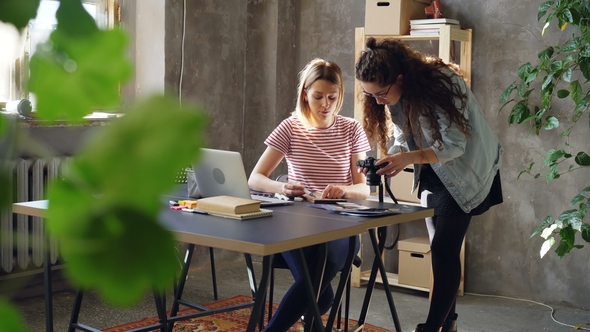 Young Professional Designer Is Discussing New Project with Female Photographer, Watching 