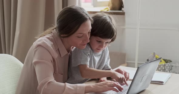 Mom and Cute Son Surfing the Internet Shopping and Playing Games on Laptop Together at Home