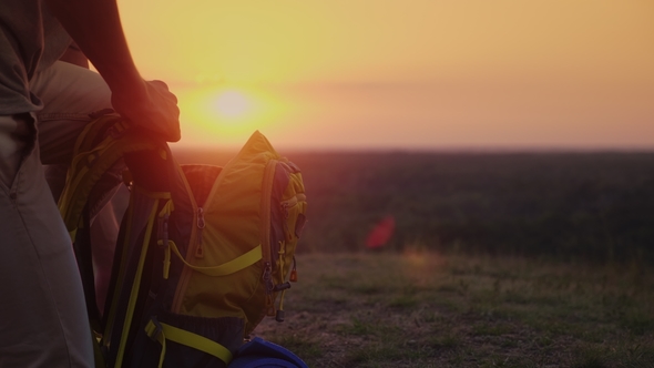 Collect Things on the Journey. The Man Puts Things in a Hike, Puts Them in a Backpack. At Sunset