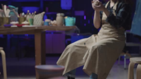 Pottery Crafting in the Art Studio a Fresh New Pot Spinning on the Wheel and a Young Woman Sitting