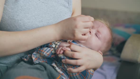 Woman Gives Nasal Drops To Little Son in Light Room Closeup