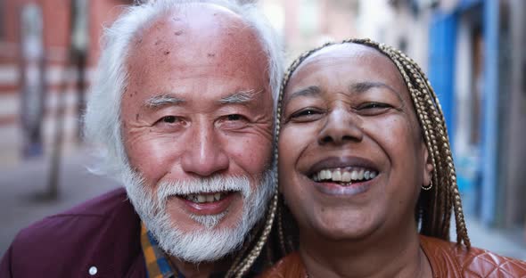 Multiracial senior couple smiling on camera outdoor