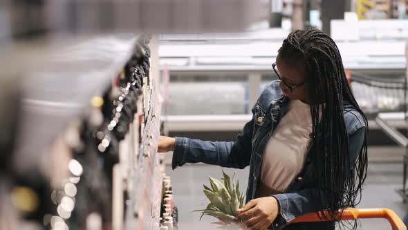 Young Lady Choosing a Bottle of Wine in a Supermarket