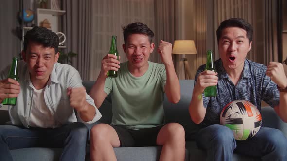 Three Asian Males Cheering And Watching Football Game On Tv And Celebrating Victory At Home