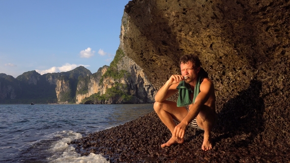 Brave Adventurist Man Is Playing Hapr Barefoot on the Slope of Sharp Island Limestone Cave