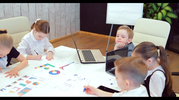 Business Children Sit at a Table and Discuss a Business Plan in a Modern Bright Office