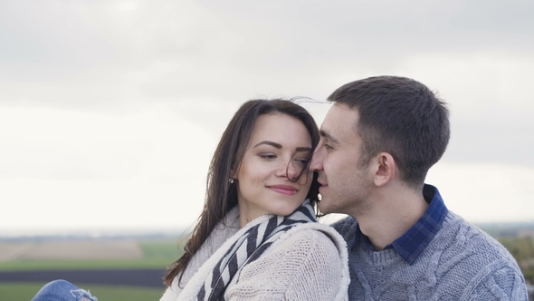 Lovely Couple Resting in Embraces on the Rock in Windy Day.